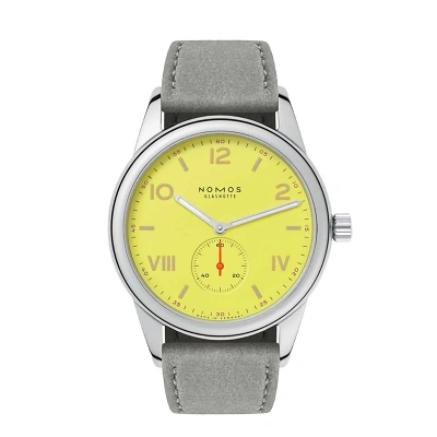 Die Armbanduhr besitzt ein leuchtend gelbes Zifferblatt mit rhodinierten Zeigern und einer kleinen roten Sekunde bei sechs Uhr. Die Zahlen sind teils arabisch, teils r&ouml;misch, orange umrandet. Das Geh&auml;use ist silbern, das Armband mattgrau.
