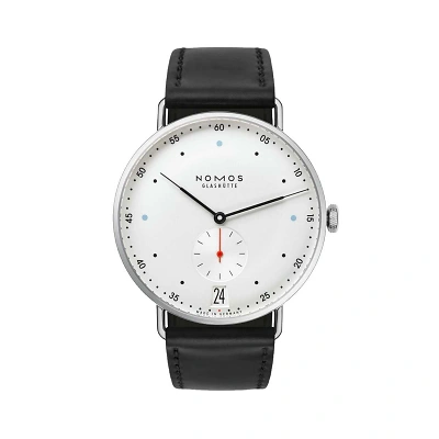 Minimalistische NOMOS-Uhr. Die Vorderansicht zeigt ein wei&szlig;es Zifferblatt mit schlanken Zeigern, kleinen Punkten als Indizes, einer kleinen Sekunde bei sechs Uhr und Datumsfenster. Schwarzes Lederband erg&auml;nzt das klare Design.