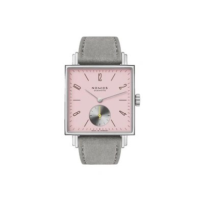 Nomos Tetra mit markant eckigem Design und rosa Zifferblatt. braunen Strichindizes und arabische Zahlen sorgen f&uuml;r klare Ablesbarkeit. Die kleine Sekunde bei 6 Uhr tr&auml;gt einen gelben Zeiger. Ein graues veganen Veloursband rundet den Look