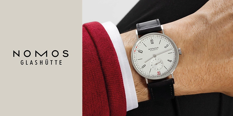 Marken&uuml;bersicht Nomos Glash&uuml;tte: Die Tangente 2Date wird am Handgelenk getragen. Mit ihrem klaren, minimalistischen Design und dem eleganten Zifferblatt verk&ouml;rpert sie die zeitlose &Auml;sthetik der Marke und die hohe Pr&auml;zision der Uhrmacherkunst.